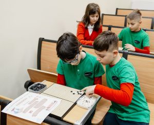 Go, un joc de strategie străvechi în care sunt implicați doi jucători; jocul este originar din China (aproximativ anii 2000 - 200 înainte de Hristos). Jocul implică înconjurarea unui teritoriu mai mare decât al adversarului pe o tablă (goban). Jucătorii plasează alternativ pietre negre și albe pe intersecțiile grilei, scopul fiind controlul spațiului și capturarea pieselor inamice.